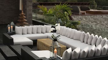 A modern outdoor seating area with a sectional sofa, cushions, and a lantern.