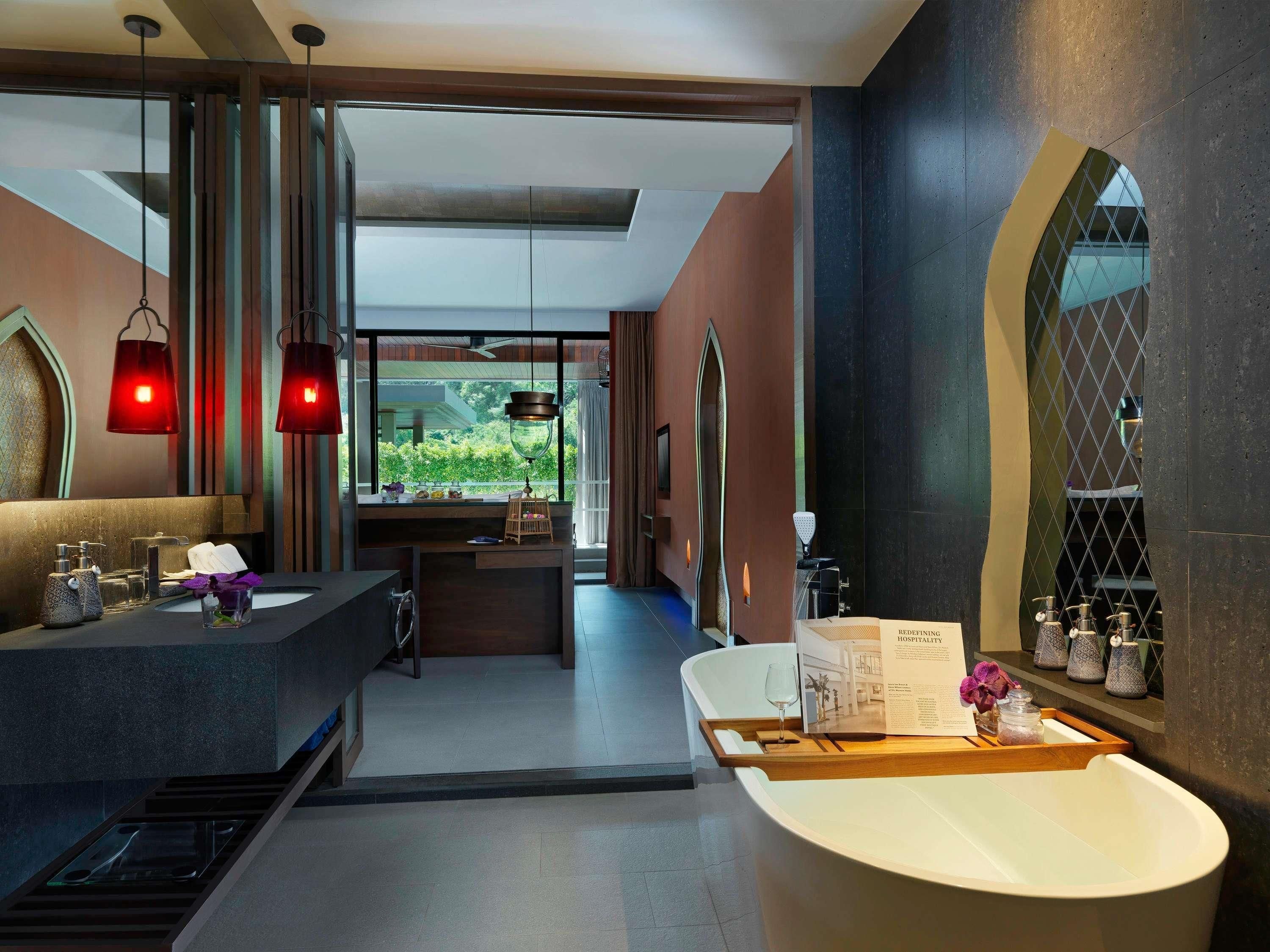 A modern bathroom with a large bathtub, a vanity with a mirror, and a window offering a view of greenery.