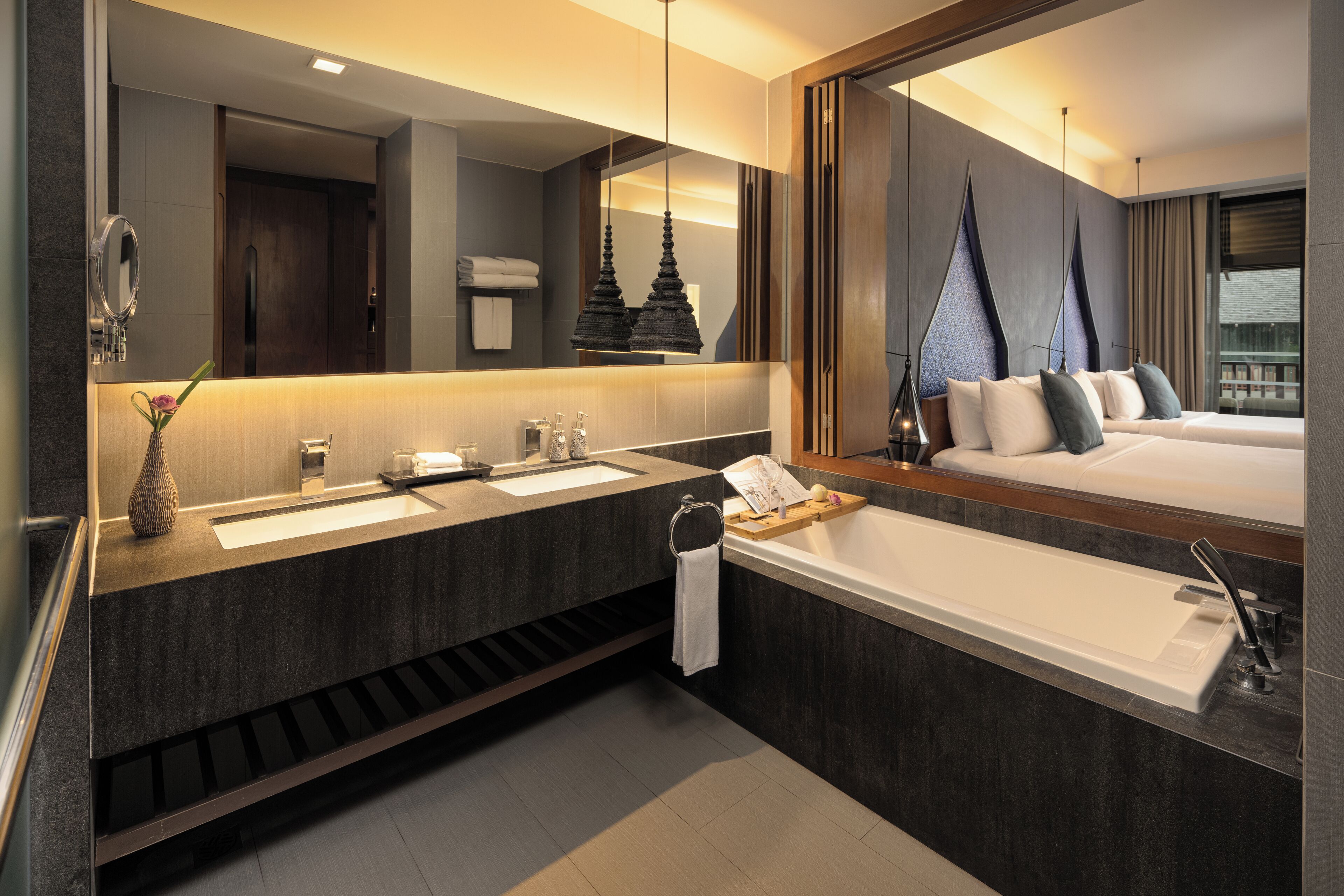 Ein modernes Badezimmer mit einem großen Spiegel, zwei Waschbecken, einer Badewanne und einem Bett mit Blick auf die Stadt.