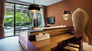 A modern hotel room with a wooden desk, a large window with a view of greenery, and a unique decorative wall piece. - Avista Hideaway Phuket Patong - MGallery (Patong)