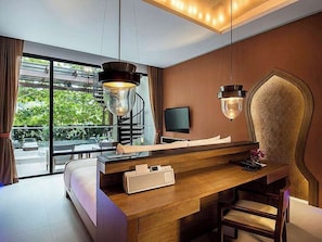 Una habitación de hotel moderna con un escritorio de madera, un ventanal con vistas a la vegetación y una pieza decorativa original en la pared.
