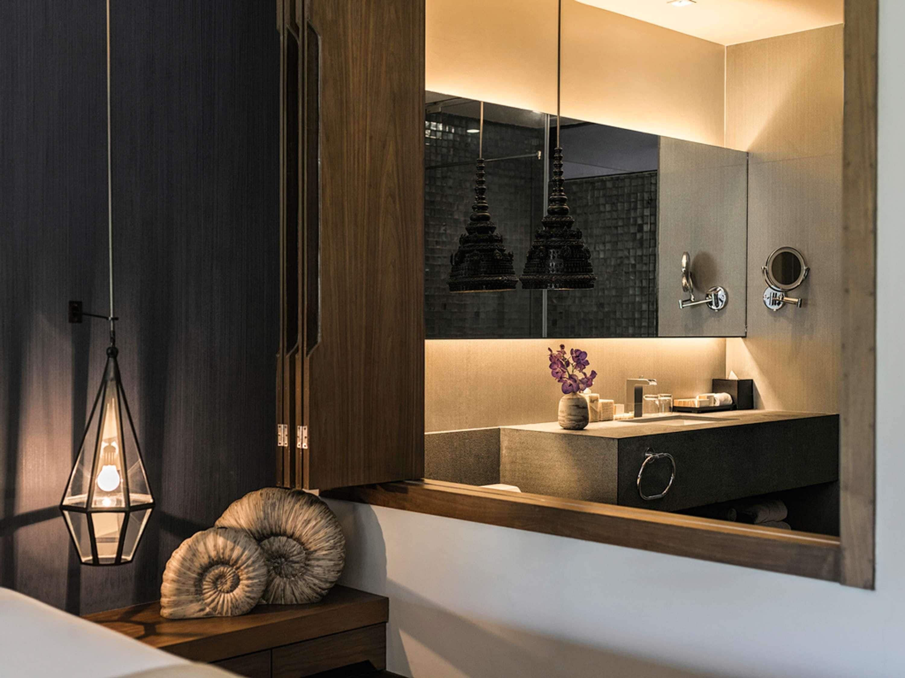 Une salle de bain moderne avec un meuble-lavabo en bois, un miroir et un luminaire suspendu.