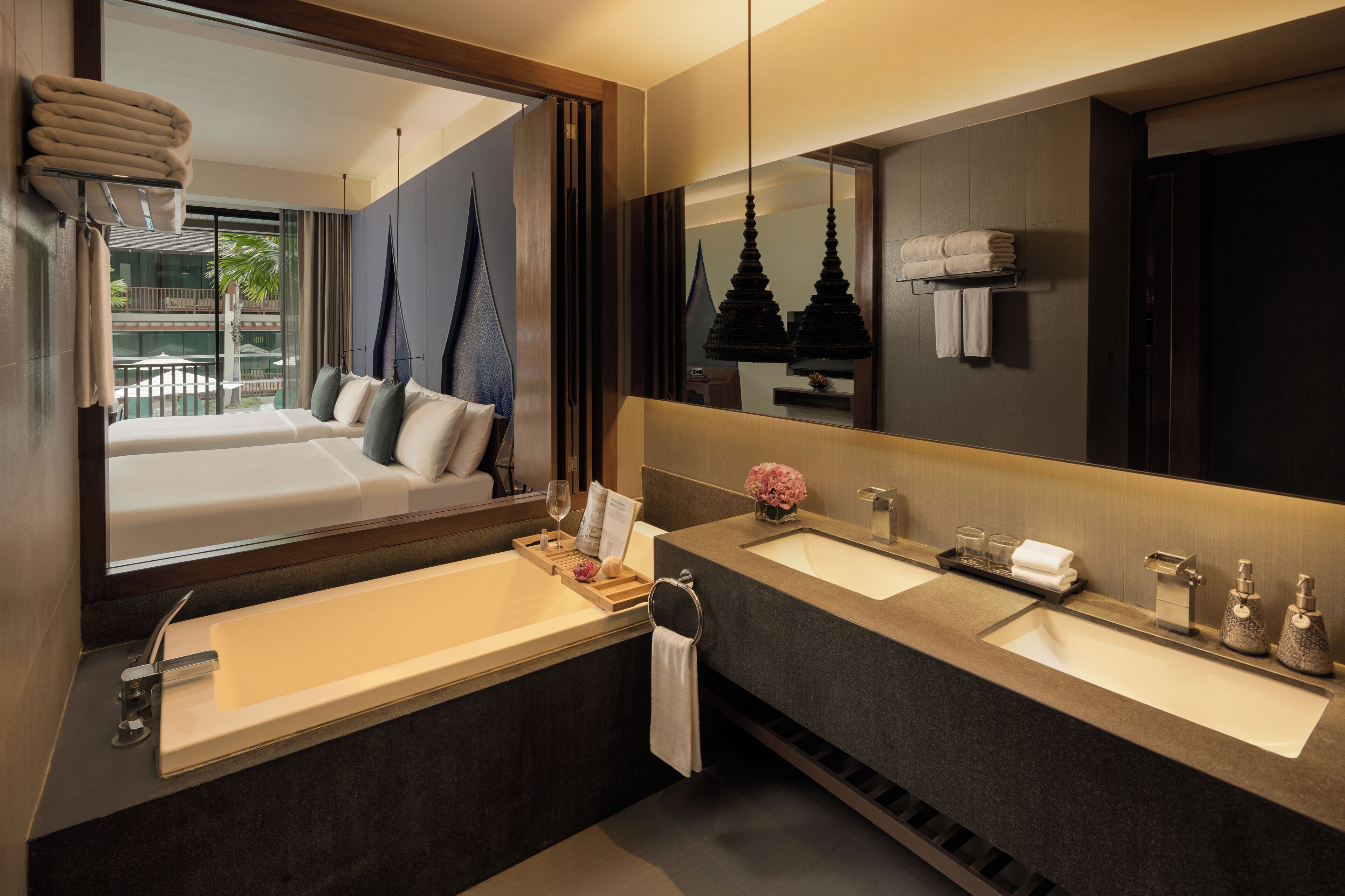 Un baño moderno con lavamanos dobles, un espejo grande y vistas a un balcón con una cama.