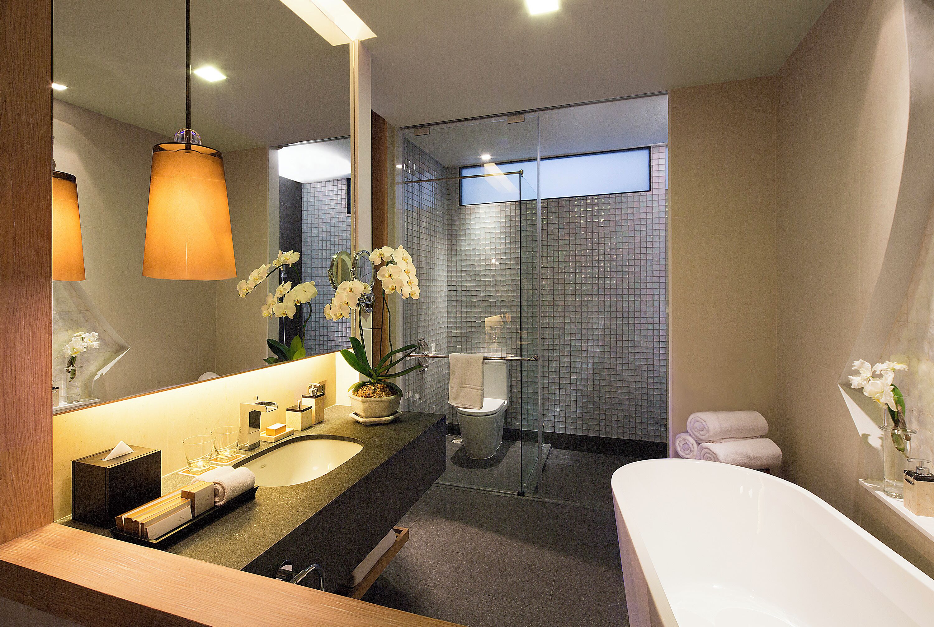 Un baño moderno con un lavamanos grande, espejo y una ducha con cerramiento de vidrio.