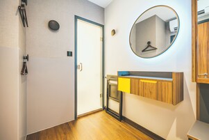 Ein Hotelzimmer mit Holzboden, einer Tür, einem Spiegel, einem Holzschrank und einem Handtuchhalter.