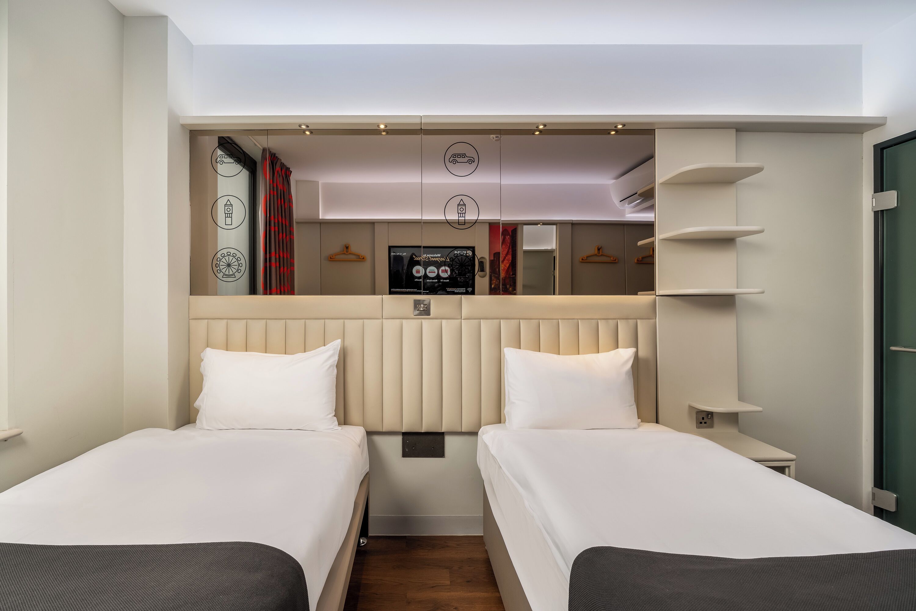 Habitación de hotel con dos camas, televisión, minibar y armario.