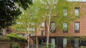 Ein modernes Ziegelgebäude mit überdachter Außenbestuhlung und einem Garten.