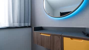 Ein modernes Badezimmer mit einem Holzlagerfläschchen, einem Spiegel mit blauer Beleuchtung und einem Fenster mit weißen Vorhängen.