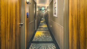 Ein Hotelgang mit Holzwänden, einem Teppich mit Sonnendesign und einer Deckenleuchte.