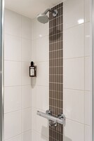 Ducha con cabezal de ducha manual, panel de control y barra para toallas.