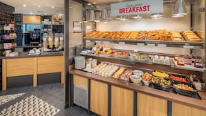 Ein Frühstücksbuffet mit verschiedenen Speisen und einem Schild mit der Aufschrift 'Enjoy your BREAKFAST'.
