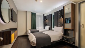 Ein Hotelzimmer mit zwei Betten, einem Fernseher, einem Spiegel und einem Kleiderschrank.