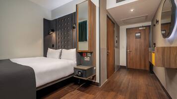Habitació d'hotel moderna amb llit, taula de nit i un mirall gran.