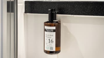 Une bouteille de shampooing pour les cheveux et le corps de la marque Naturals Remedies, dotée d’un distributeur noir à pompe, portant le numéro 16, dans une salle de bain.