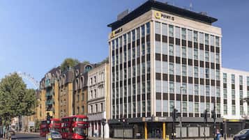 Un edificio moderno con varios pisos, amplias ventanas y un letrero llamativo de un hotel.