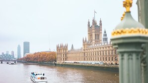 A river with a boat, a large historic building with towers, and a modern skyscraper in the background. - Point A London Waterloo (London)