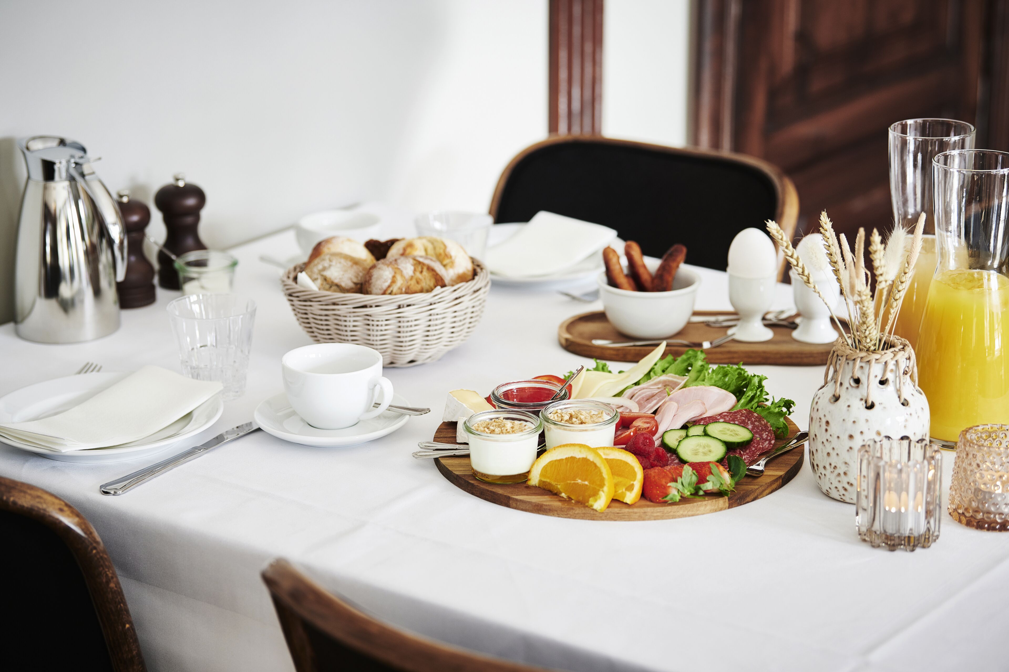 A breakfast setting with a variety of food items, including bread, eggs, and a fruit platter.