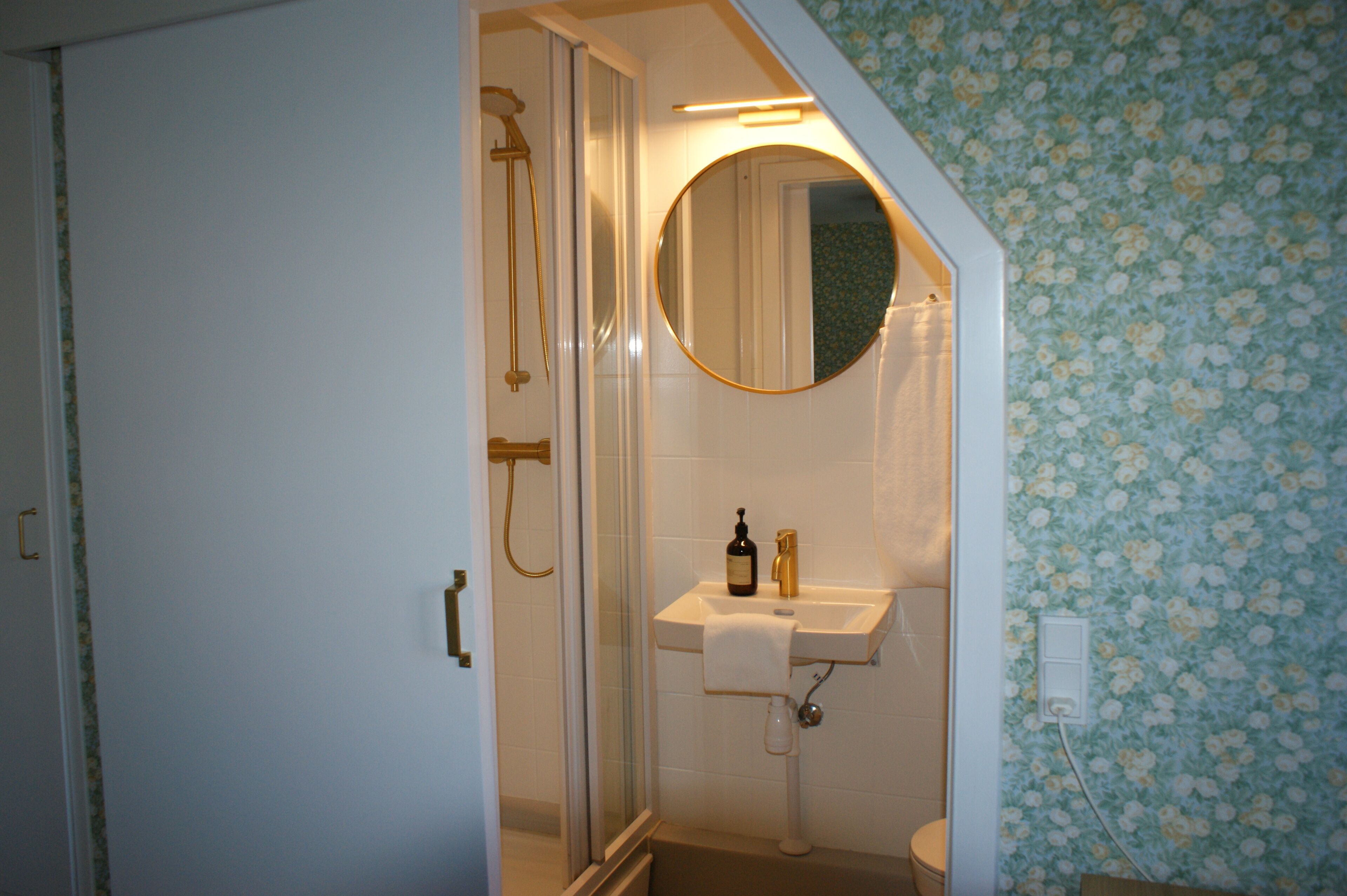 Een badkamer met een douche, een wastafel met spiegel en een toilet.