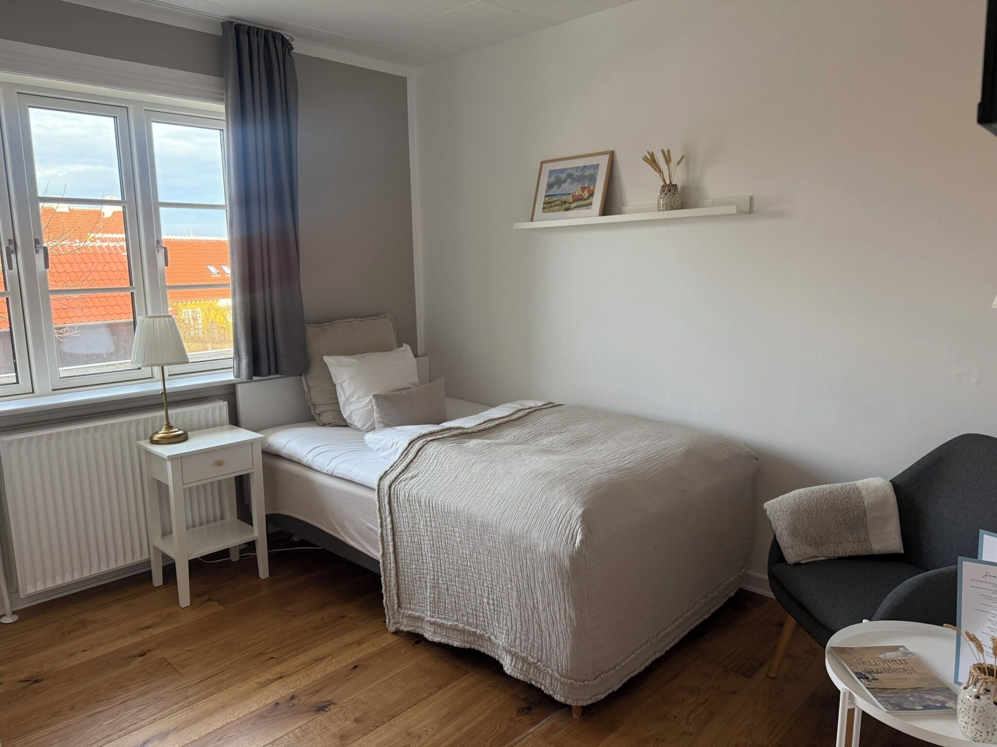 A bedroom with a bed, bedside table, lamp, and a chair.