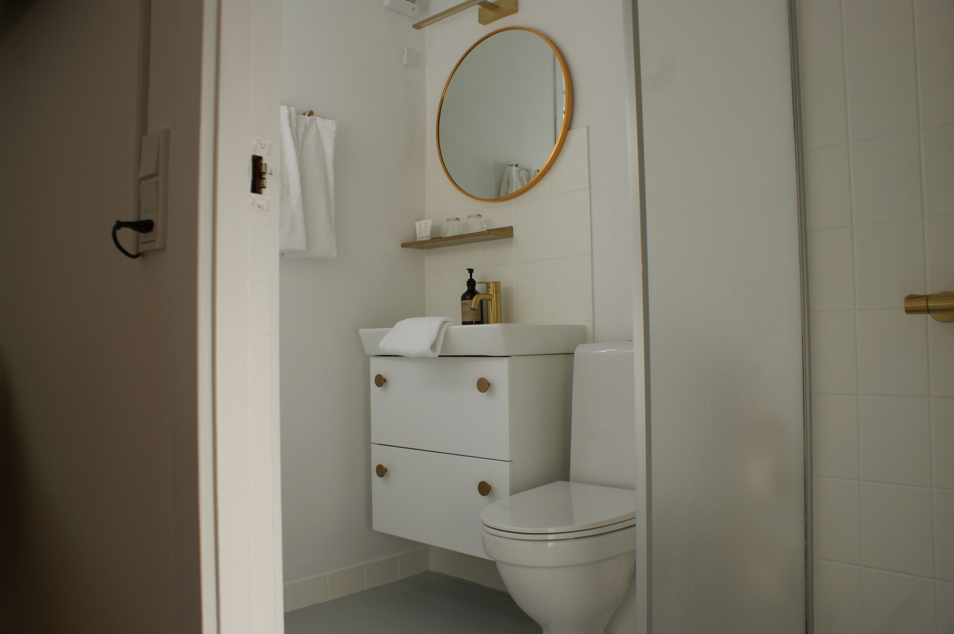 A bathroom with a white toilet, a sink with a gold faucet, a mirror, and a towel hanging on the wall.