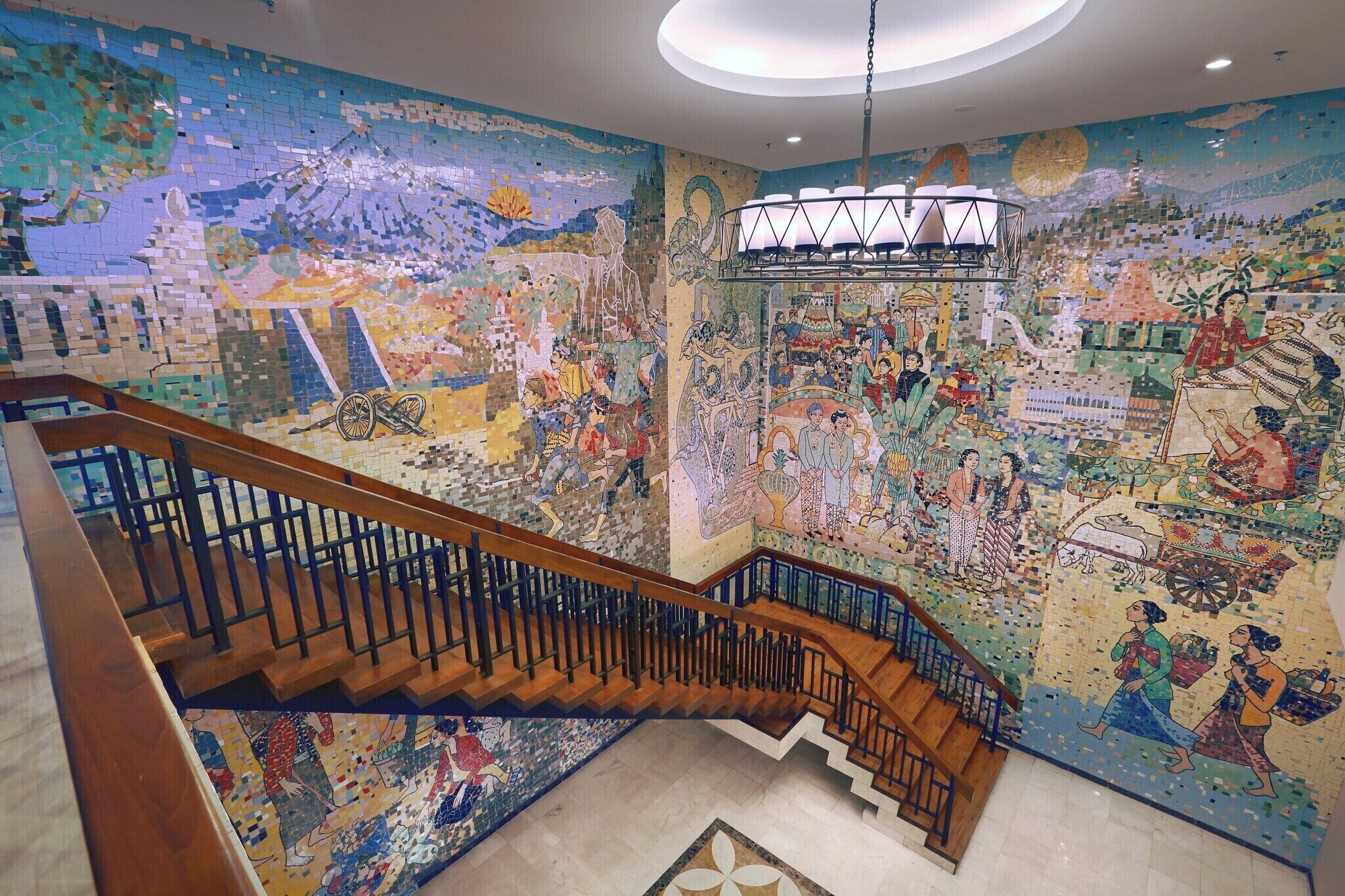 A staircase with a mosaic wall depicting various scenes and figures.