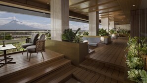 A modern outdoor lounge area with wooden flooring, seating, and potted plants.