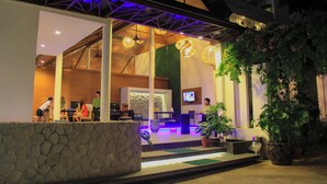 An indoor area with a reception desk, seating, and a television screen. - The Viridian Resort (Patong)