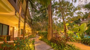 A pathway lined with tropical plants and trees, leading to a building with a balcony. - The Viridian Resort (Patong)
