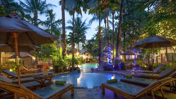 A pool area with lounge chairs and umbrellas, surrounded by palm trees and tropical plants. - The Viridian Resort (Patong)