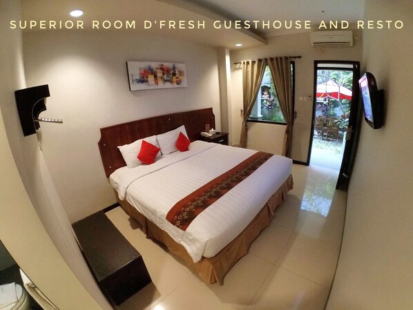 A hotel room with a bed, a TV, a window with curtains, and a wall-mounted air conditioner.
