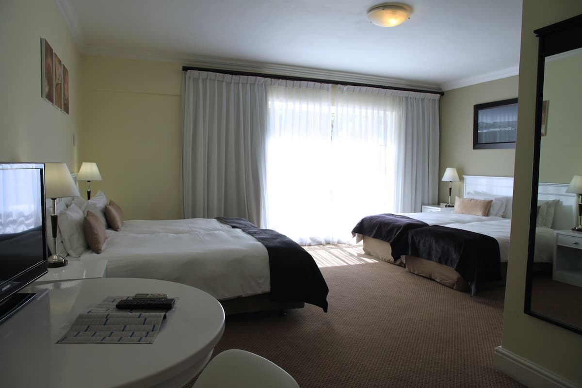 Una habitación de hotel con dos camas, un escritorio con ordenador y televisor.