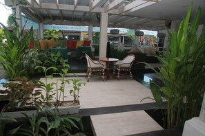 An indoor seating area with wicker chairs, potted plants, and a tiled floor. - The Watergarden (Karangasem)