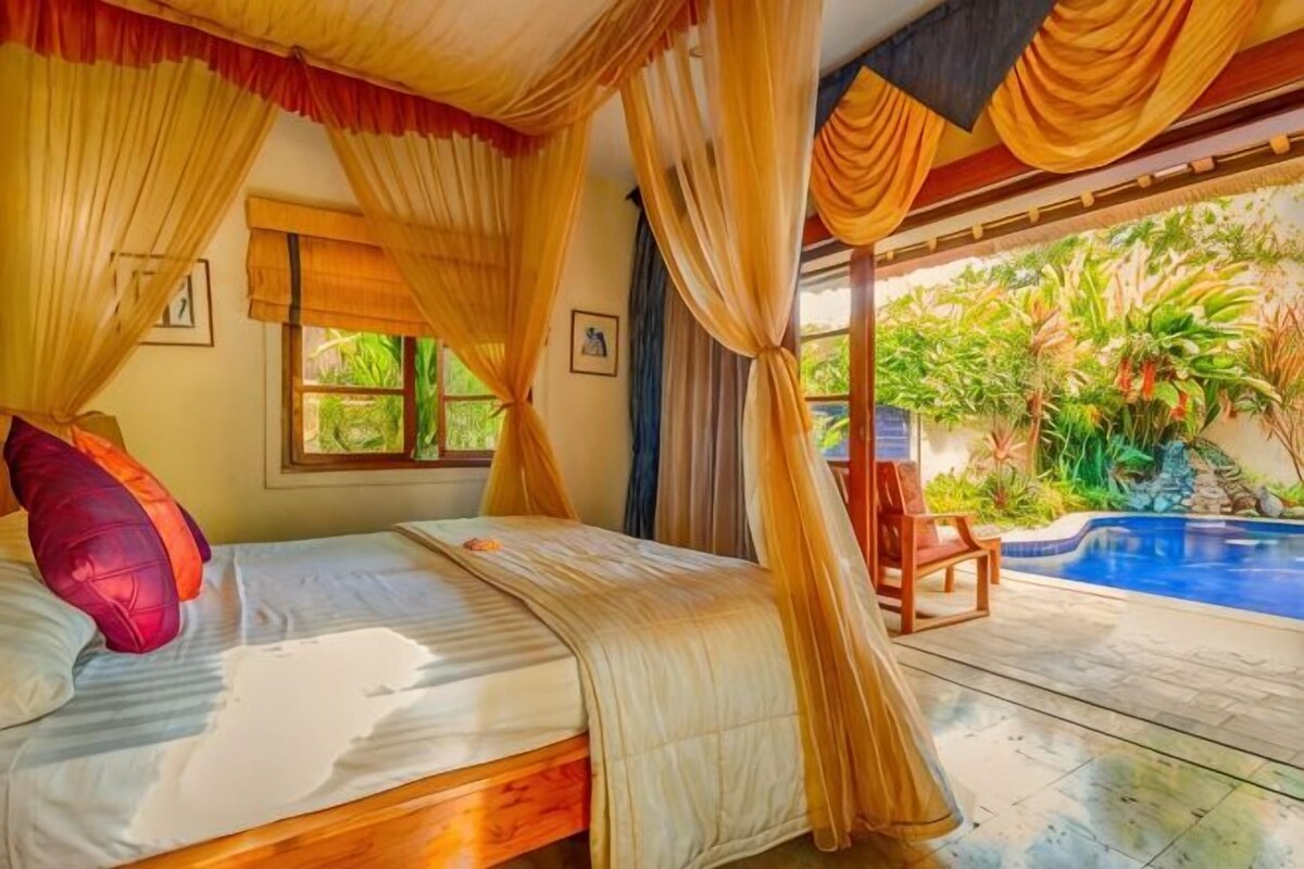Un dormitorio con cama, cortinas, una ventana y vistas a una piscina y vegetación.