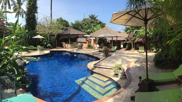 Una piscina al aire libre, sillones reclinables de piscina