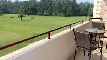 Enjoy a peaceful view from this balcony overlooking a lush lawn and trees.