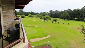 Un balcón con mobiliario de mimbre con vistas a un campo de golf.