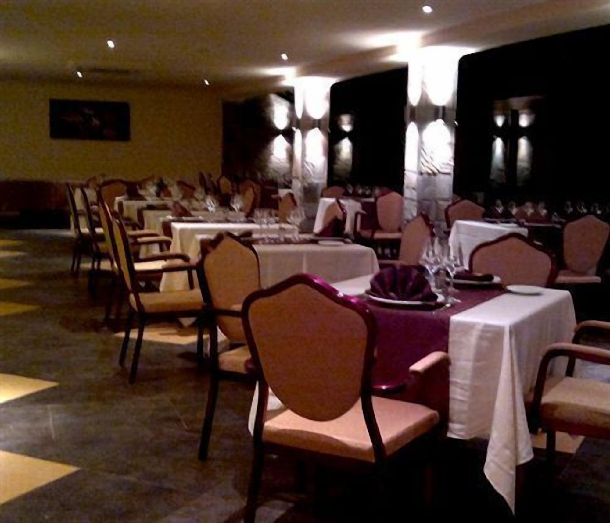 A banquet hall with round tables, chairs, and a stage.