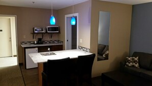 A compact living space with a kitchenette, a dining area, and a seating area. - Rock Creek Hotel (Sabetha)