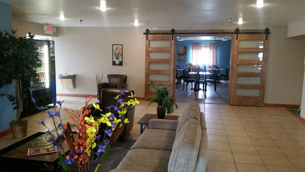 A lobby with a reception desk, seating area, and a dining area visible through an open door. - Rock Creek Hotel (Sabetha)
