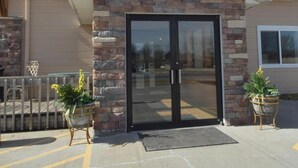 A building with a stone facade, a glass entrance, and a clear sky. - Rock Creek Hotel (Sabetha)