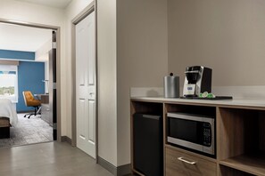 A modern kitchen with a built-in microwave, coffee maker, and a small refrigerator.