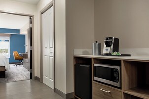 Una cocina moderna equipada con microondas, cafetera y un refrigerador pequeño.