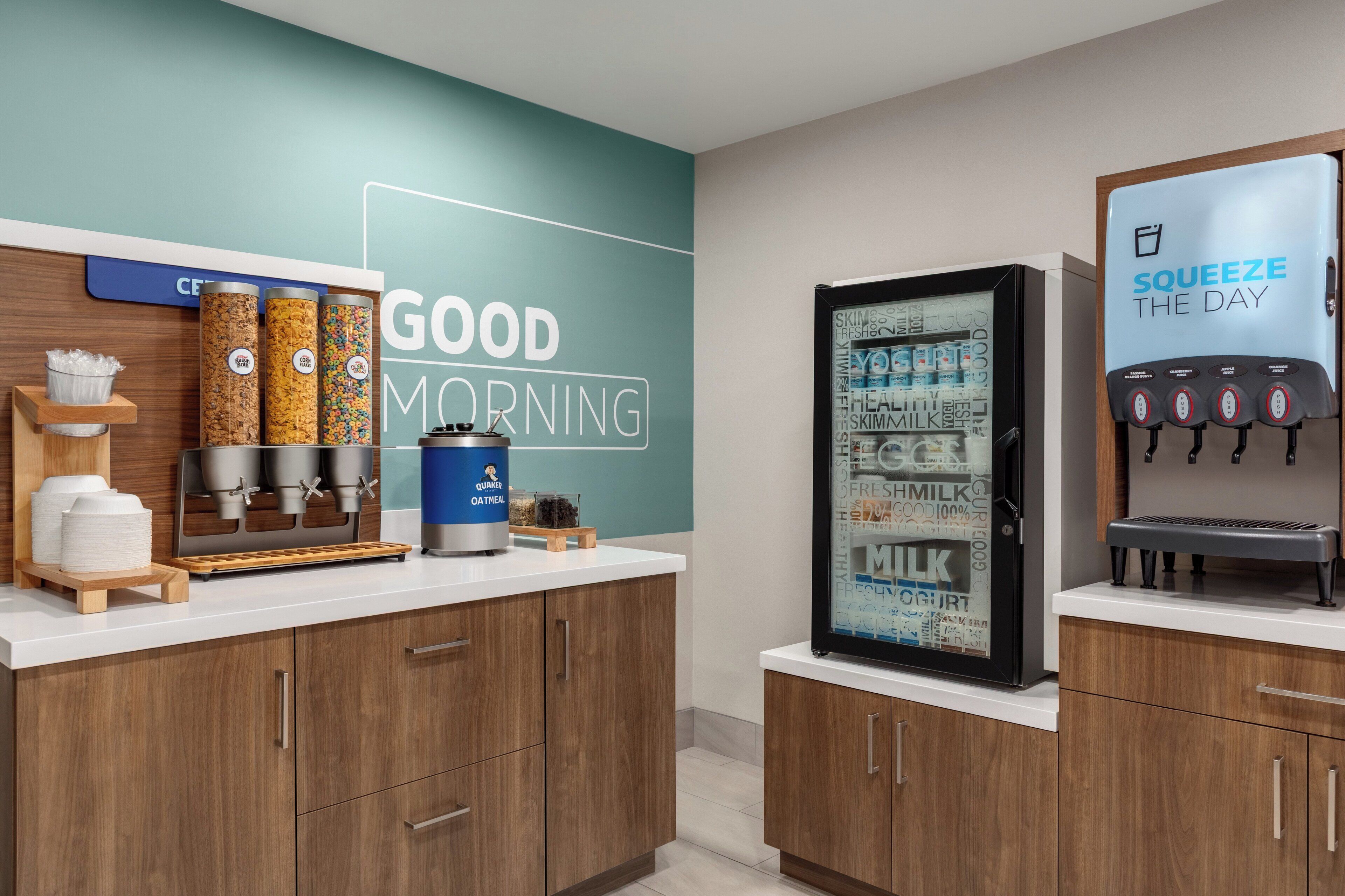 A kitchenette with a coffee machine, a refrigerator, and a wall with a 'Good Morning' sign.