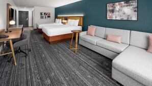 Una habitación de hotel con cama, sofá, escritorio y silla.