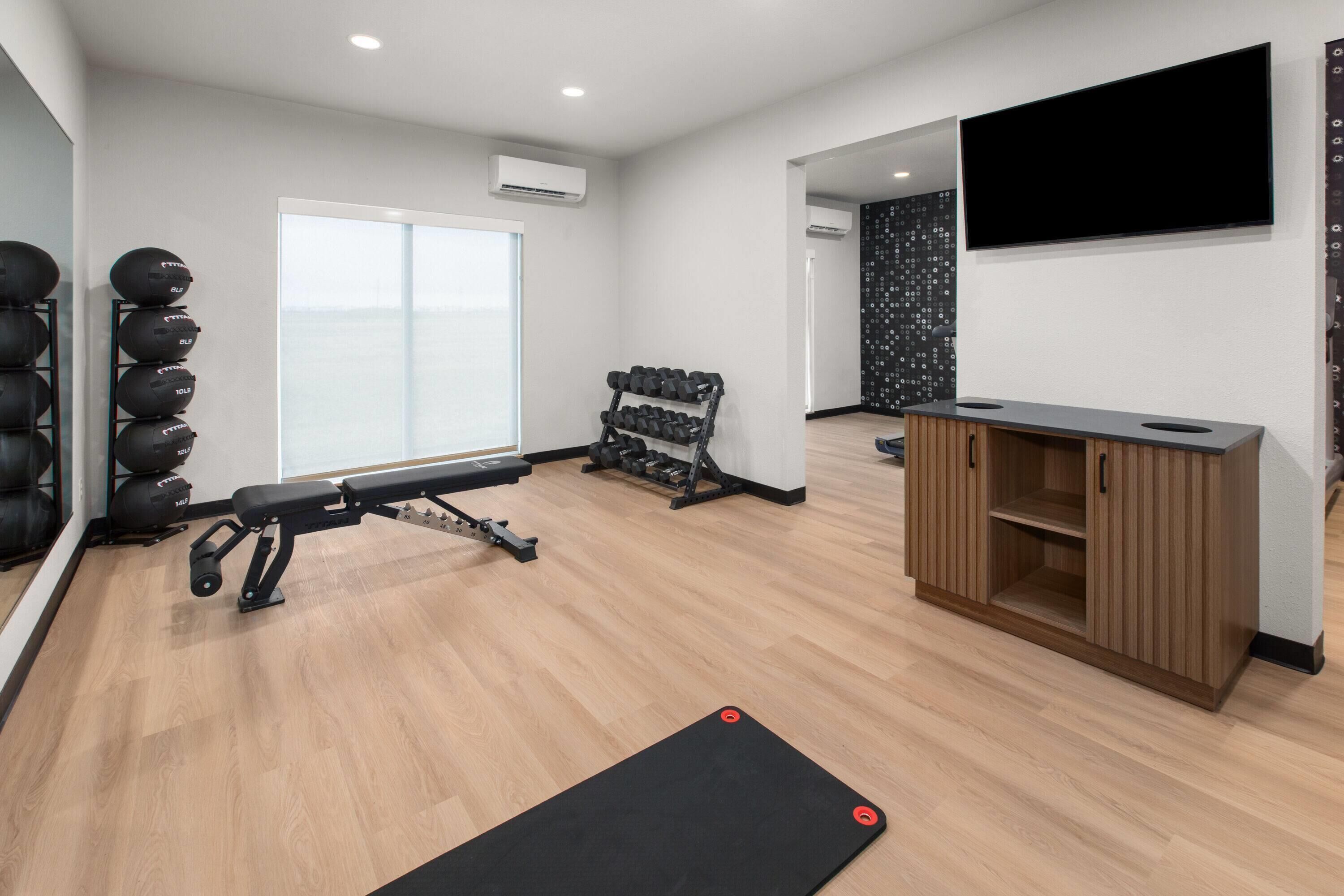Une salle de sport équipée de matériel d’exercice, d’un téléviseur et d’une armoire en bois.