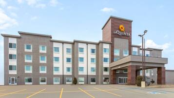 Un hotel dal design moderno, con un cartello ben visibile 'La Quinta', un parcheggio con posti delimitati e un ingresso coperto.