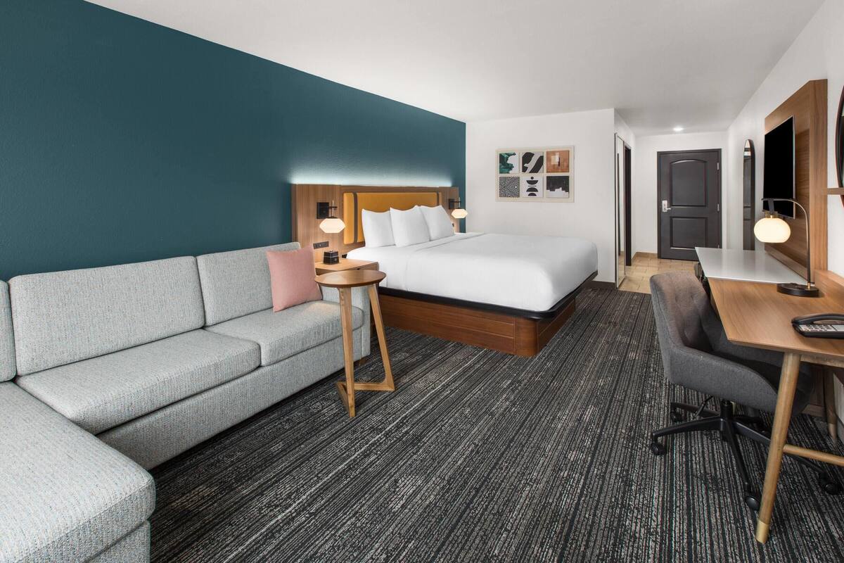 Una habitación de hotel con cama, sofá, escritorio y una mesita.