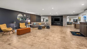 Un salón amplio con sofá, sillones, otomanas y un televisor de pantalla plana.