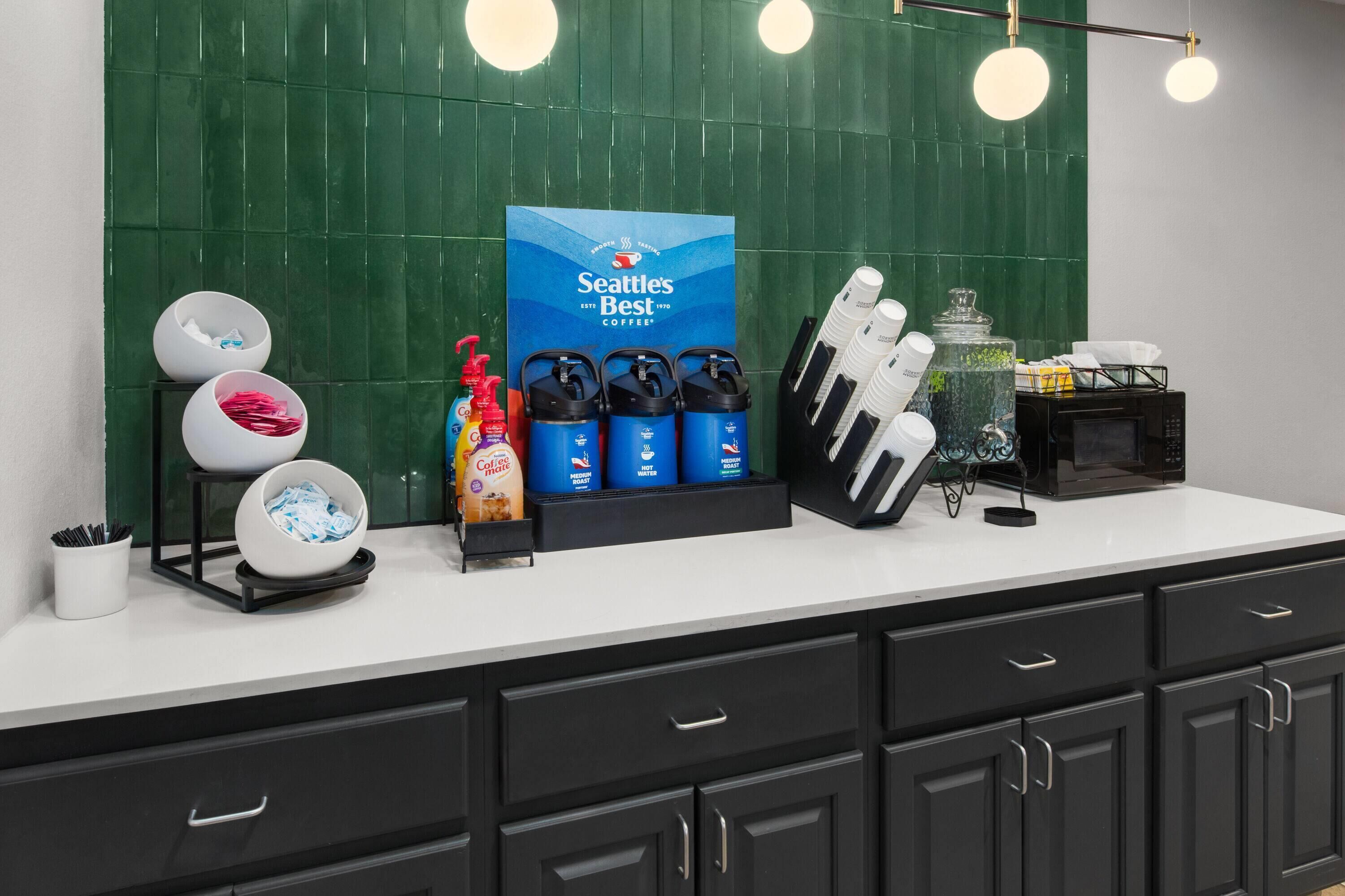 A kitchen counter with coffee dispensers, a coffee machine, and a microwave.