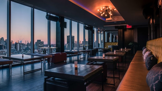 Un interior moderno con amplios ventanales, vistas a la ciudad y una zona de bar.